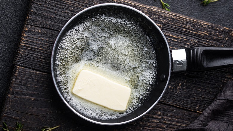 Partially melted butter in a pan on a black rustic board