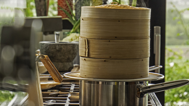 A stack of bamboo steamers in a pot on a stovetop.