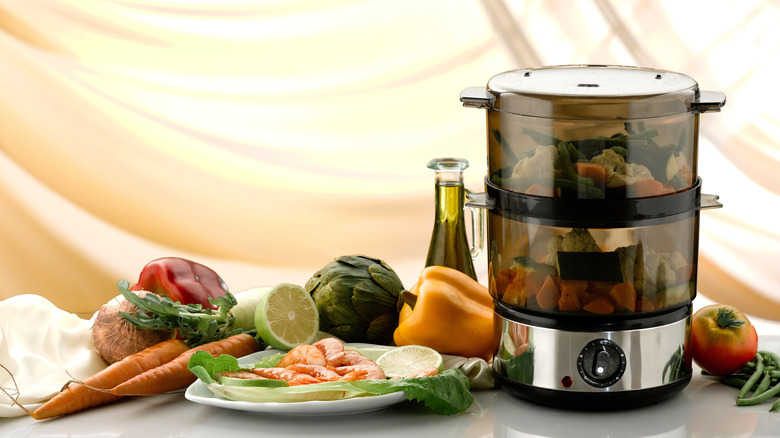 An electric steamer with vegetables on a counter.
