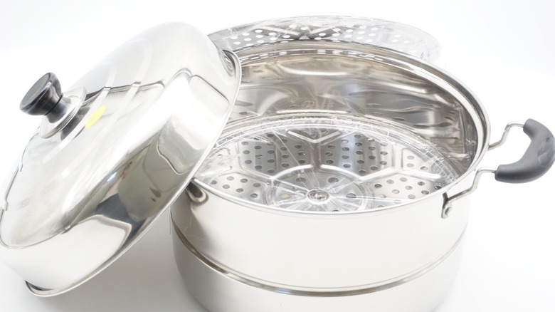A metal steamer pot with a glass lid.