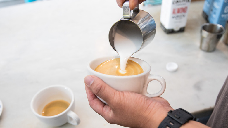 Pouring frothed milk into espresso