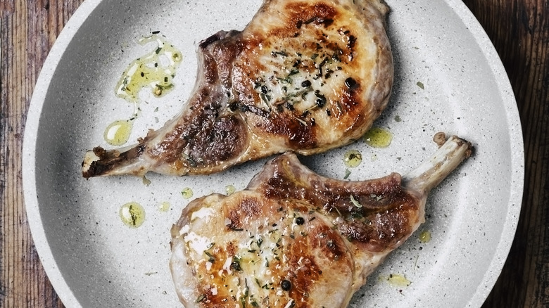 Pork chops on a plate with herbs and oil