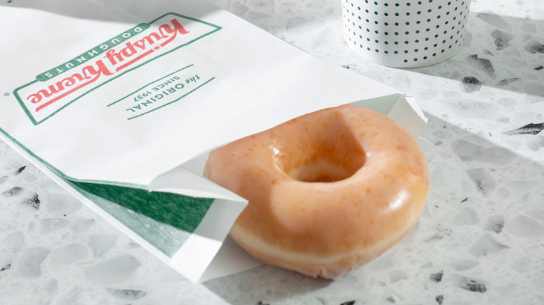 A single Krispy Kreme glazed doughnuts rests on a table