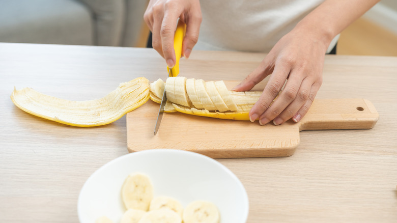 Someone slicing bananas on a cutting board