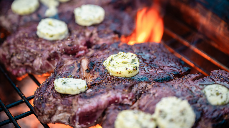 Ribeye steaks on a grill with compound butter on top