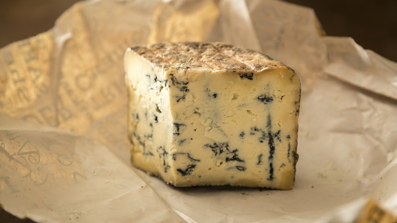 A large slice of blue cheese sitting on paper