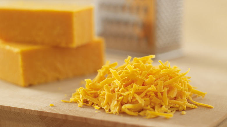 grated cheddar cheese next to cheddar blocks