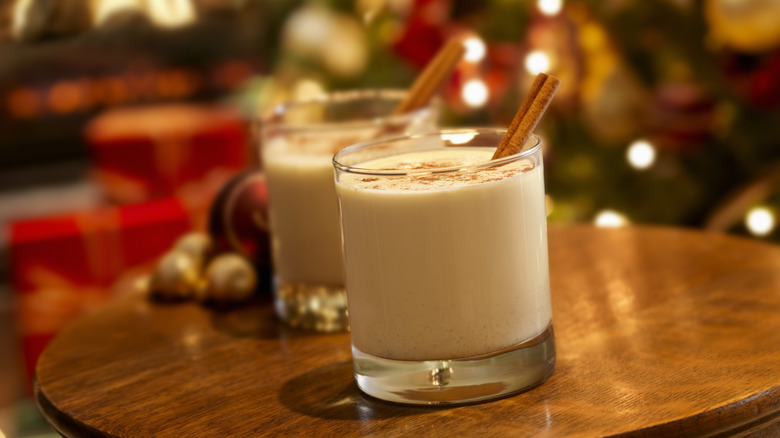 Two glasses of eggnog with cinnamon sticks