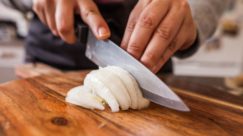 Slicing a white onion with a knife