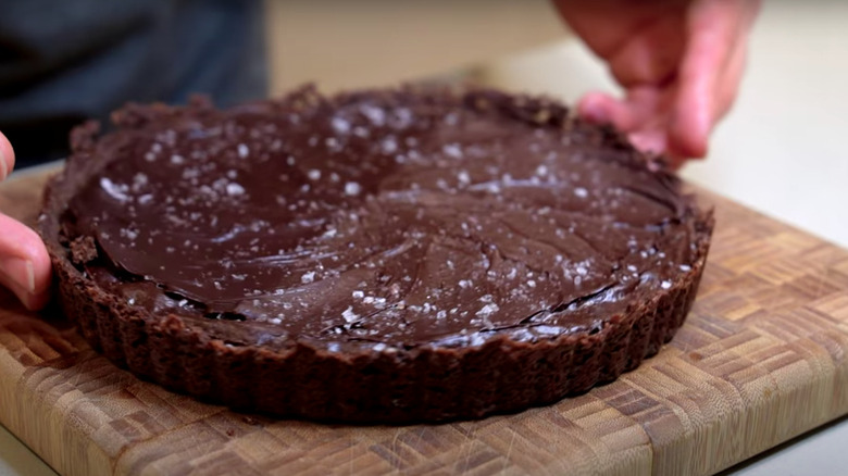 Cook holding dark chocolate tart