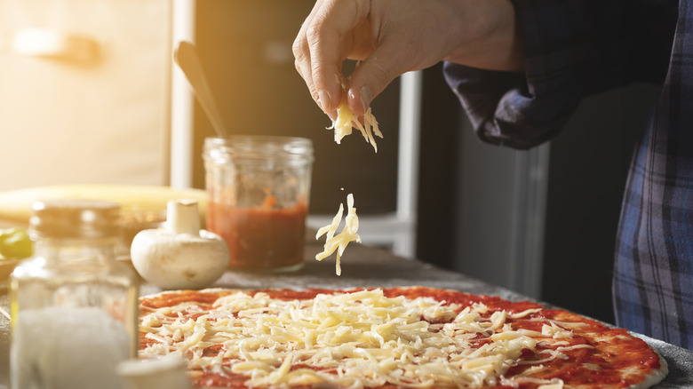 A person cooking Italian Vegetarian Pizza with cheese and mushrooms
