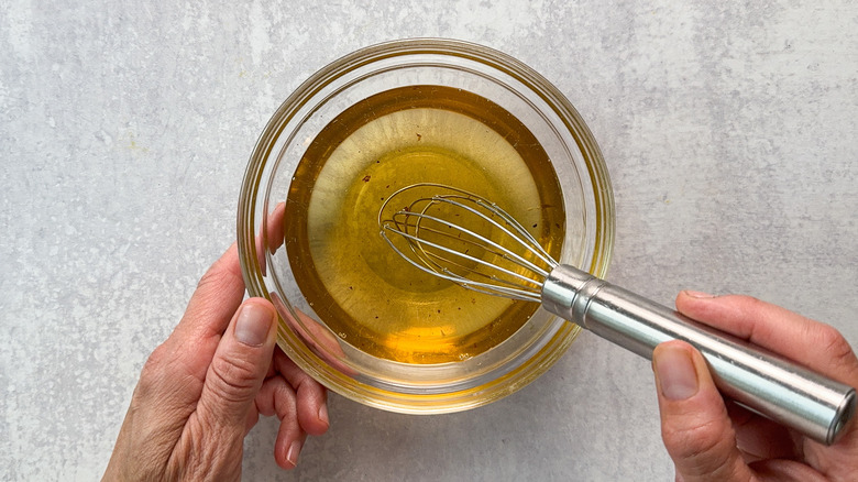 Whisking together bacon fat and avocado oil in small glass bowl with mini whisk