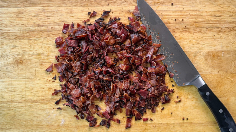 Chopped cooked bacon on cutting board with chef's knife