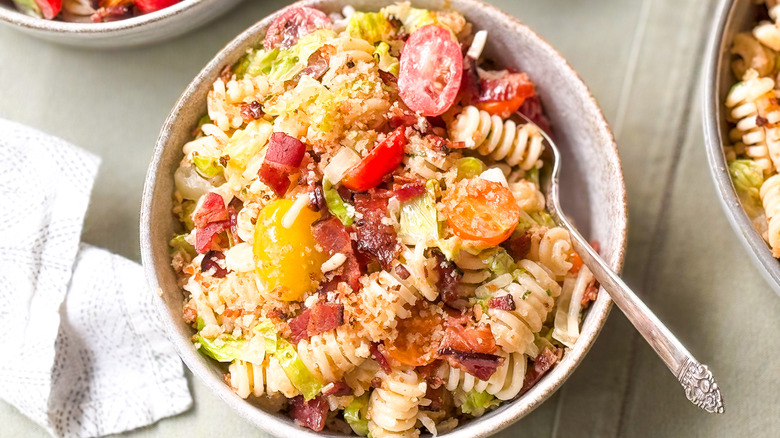 Over-the-top BLT pasta salad in serving bowl on table with fork