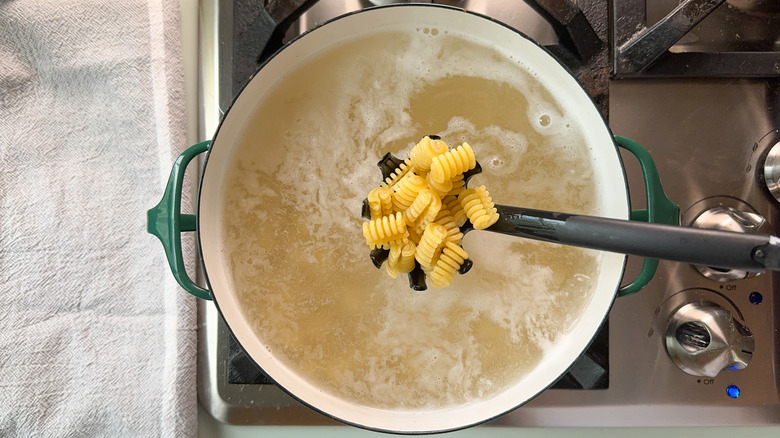 Radiatore pasta cooking in pot on stovetop with pasta spoon