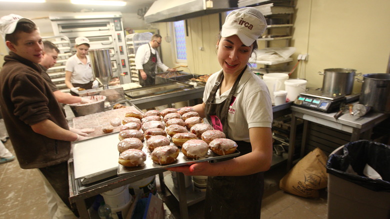 Baker carrying a tray of paczki.