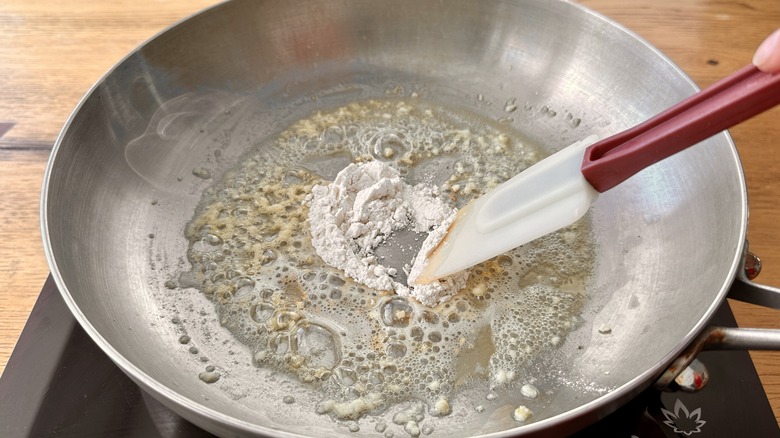 garlic, melted butter, and flour in a metal frying pan with a spatula