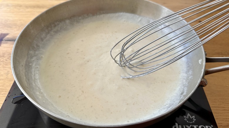 white sauce in a metal frying pan with a whisk