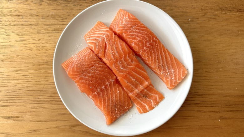 raw salmon fillets on a white plate