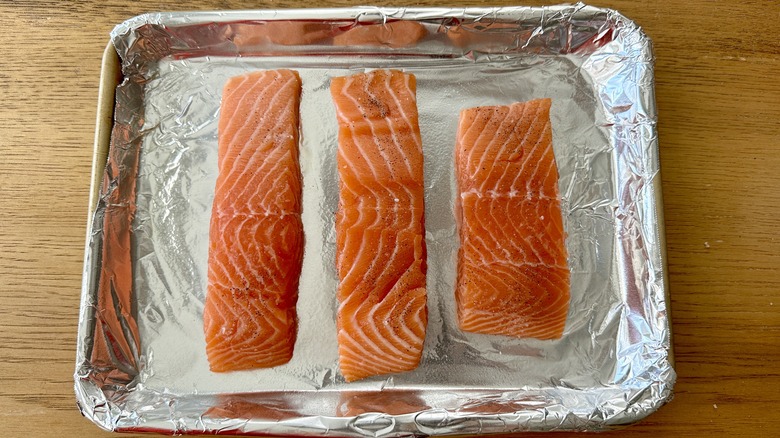 raw salmon fillets on a foil-lined baking pan