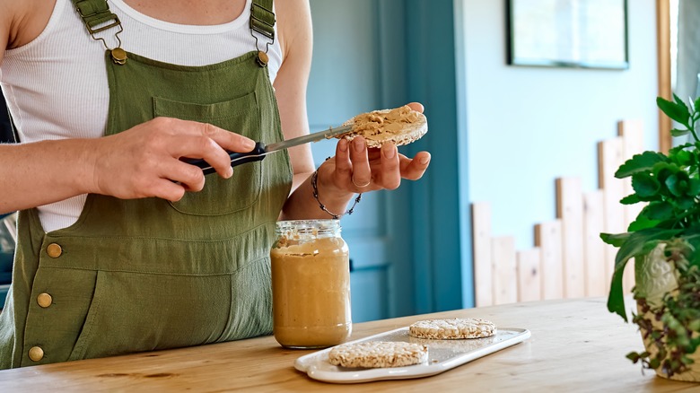 Spreading peanut butter on rice cake