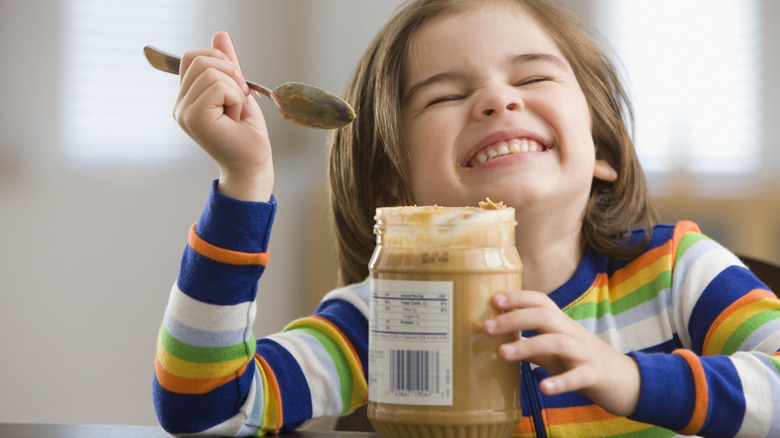 Child eating peanut butter from jar