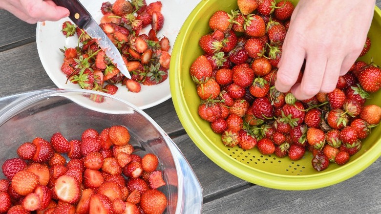 A person hulling strawberries in preparation for peeling