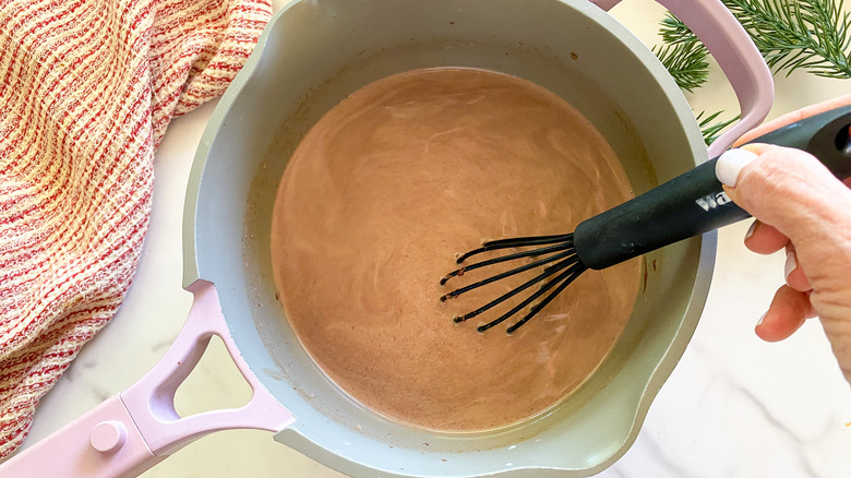 Hand whisking hot chocolate in pot
