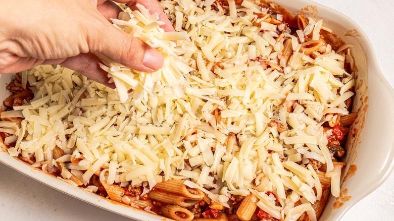 hand sprinkling cheese onto pasta