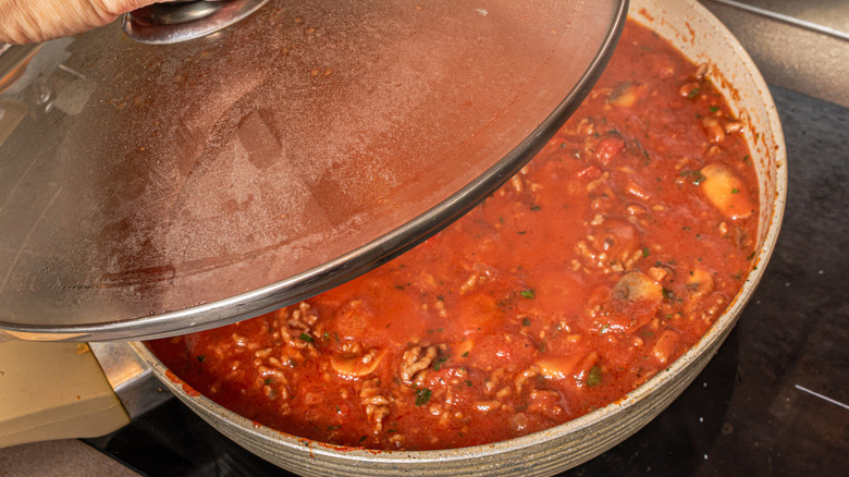 lid covering tomato sauce in pan