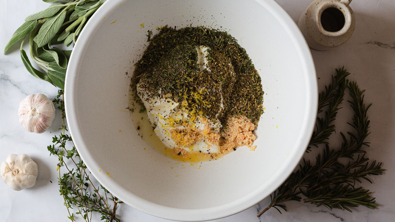 marinade ingredients in white bowl with herbs around