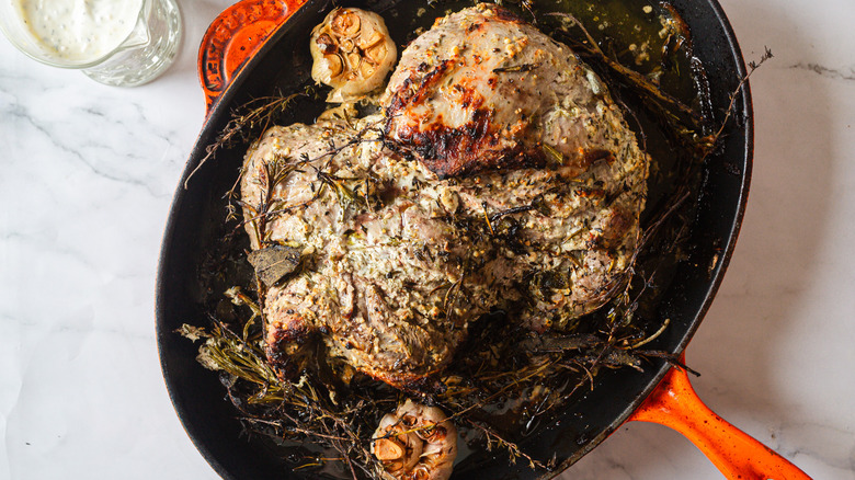 Overhead view of leg of lamb with garlic and sage and sauce