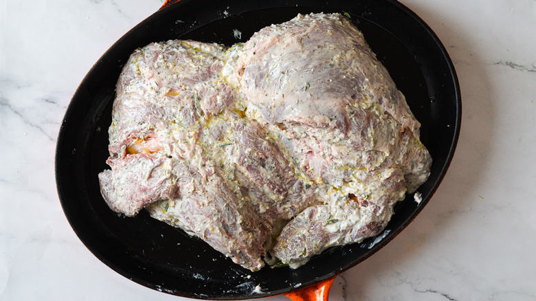 Overhead view of uncooked leg of lamb in a roasting pan