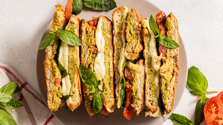 Four half pesto caprese paninis stacked on a plate