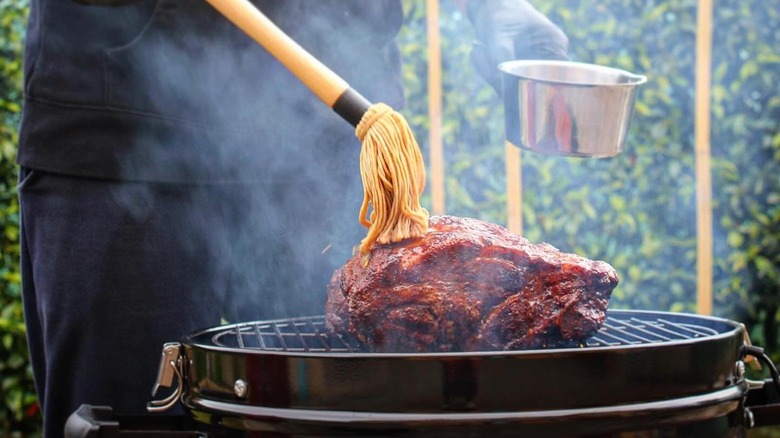 Applying sauce to barbecued meat with mop