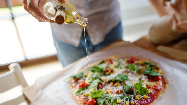 Drizzling olive oil onto fresh pizza