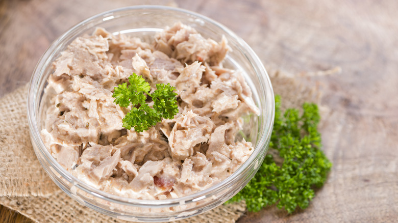 A bowl of tuna salad with a sprig of parsley on top