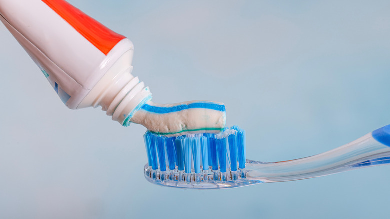 Toothpaste being squeezed onto a toothbrush.