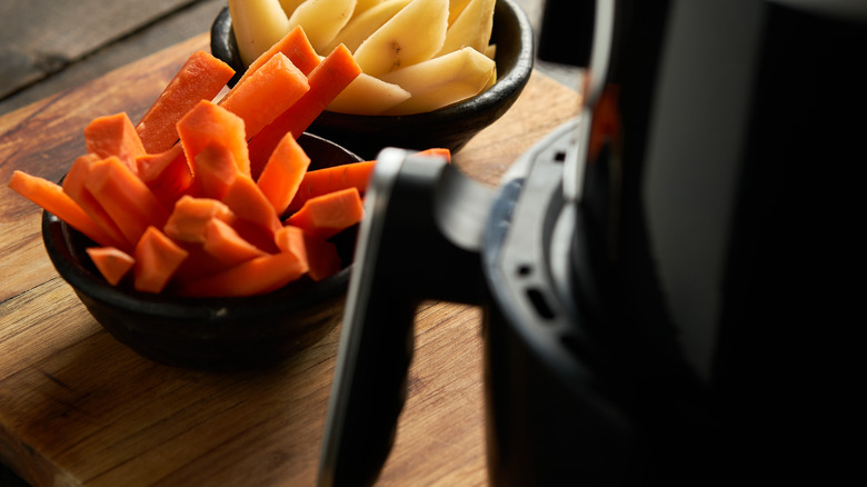 Potatoes and carrots next to airfryer