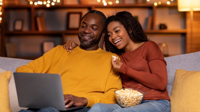 Couple sharing popcorn on couch