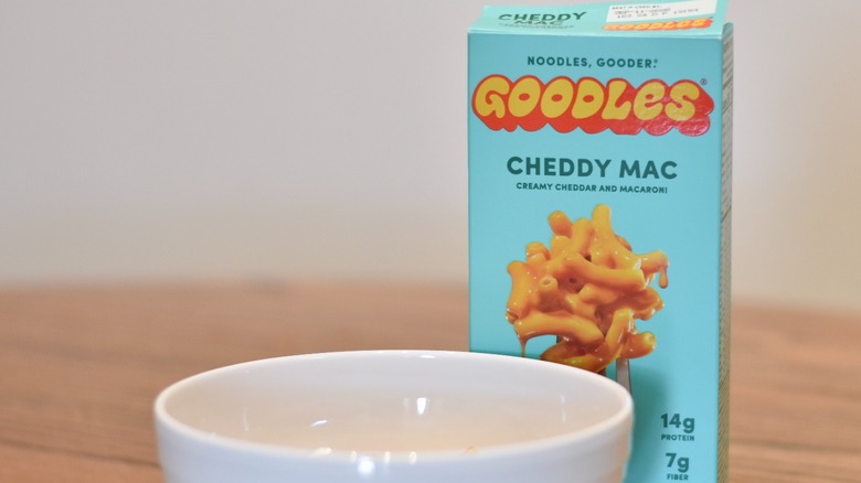 A box of Goodles cheddy mac next to a white bowl