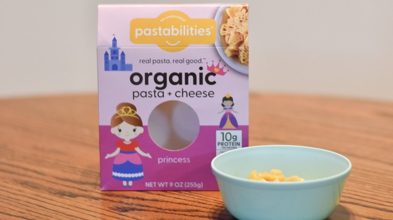 A Pastabilities box of pasta and cheese next to a bowl of macaroni and cheese