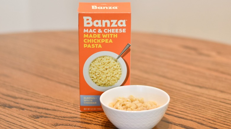 A box of Banza chickpea mac and cheese next to a bowl of macaroni