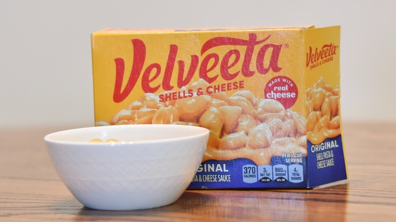 A box of Velveeta shells and cheese is next to a white bowl