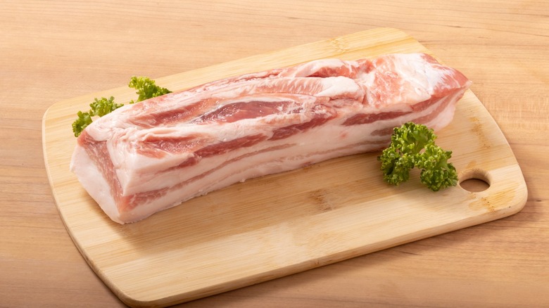 Raw slab of pork belly on a cutting board