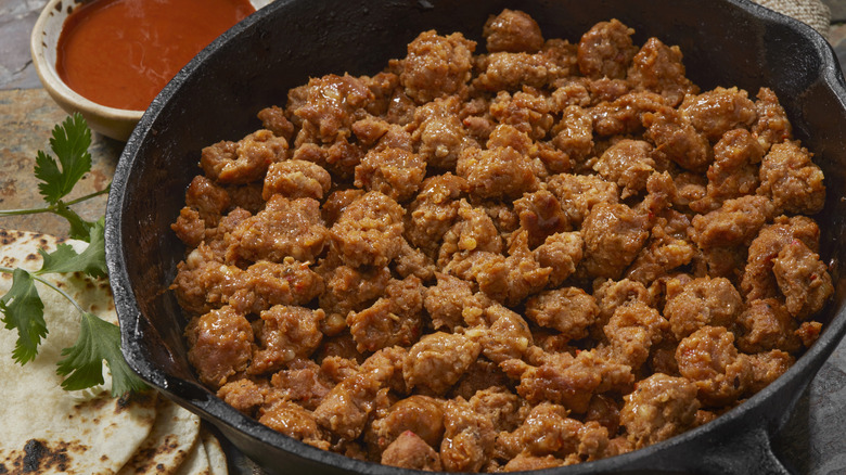 Browned Mexican chorizo is displayed in a cast iron skillet.