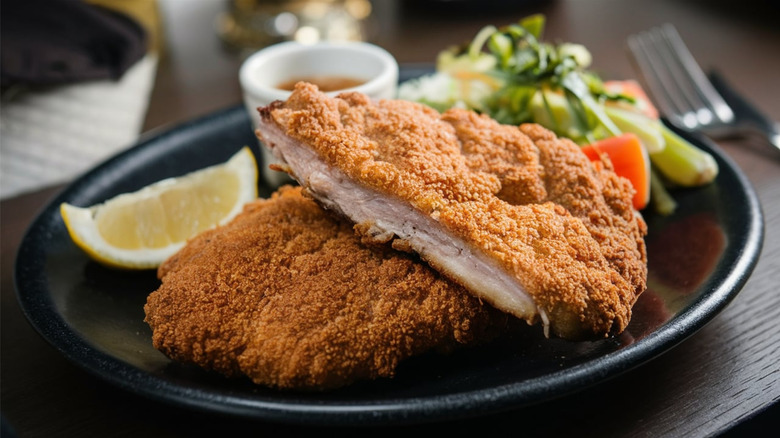 pork schnitzel sliced in half on plate with vegetables