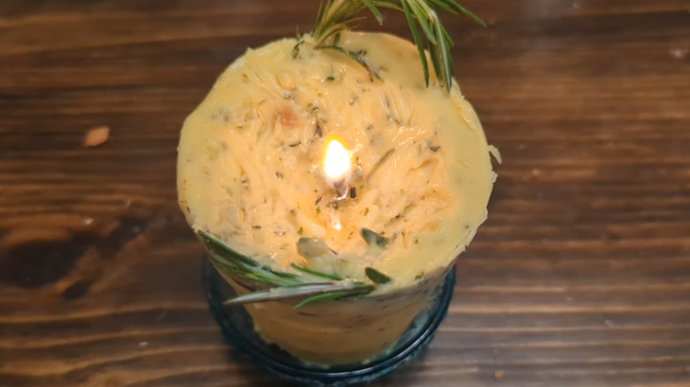 Lit butter candle with rosemary on counter