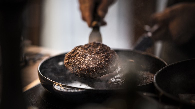 Cooking a burger patty in a pan on the stove