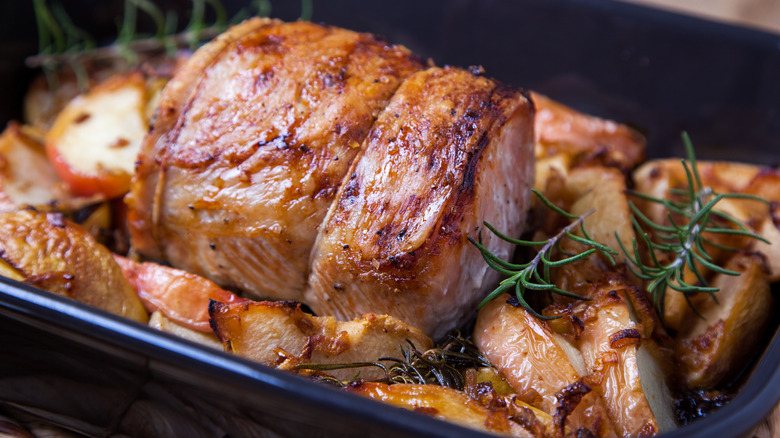 Roasted pork loin in a pan with sprigs of rosemary